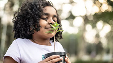 young AFrican American girl smelling potted plant